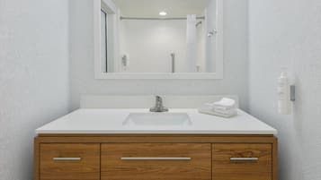 A bathroom with a white sink, wooden vanity, and a mirror above the sink.