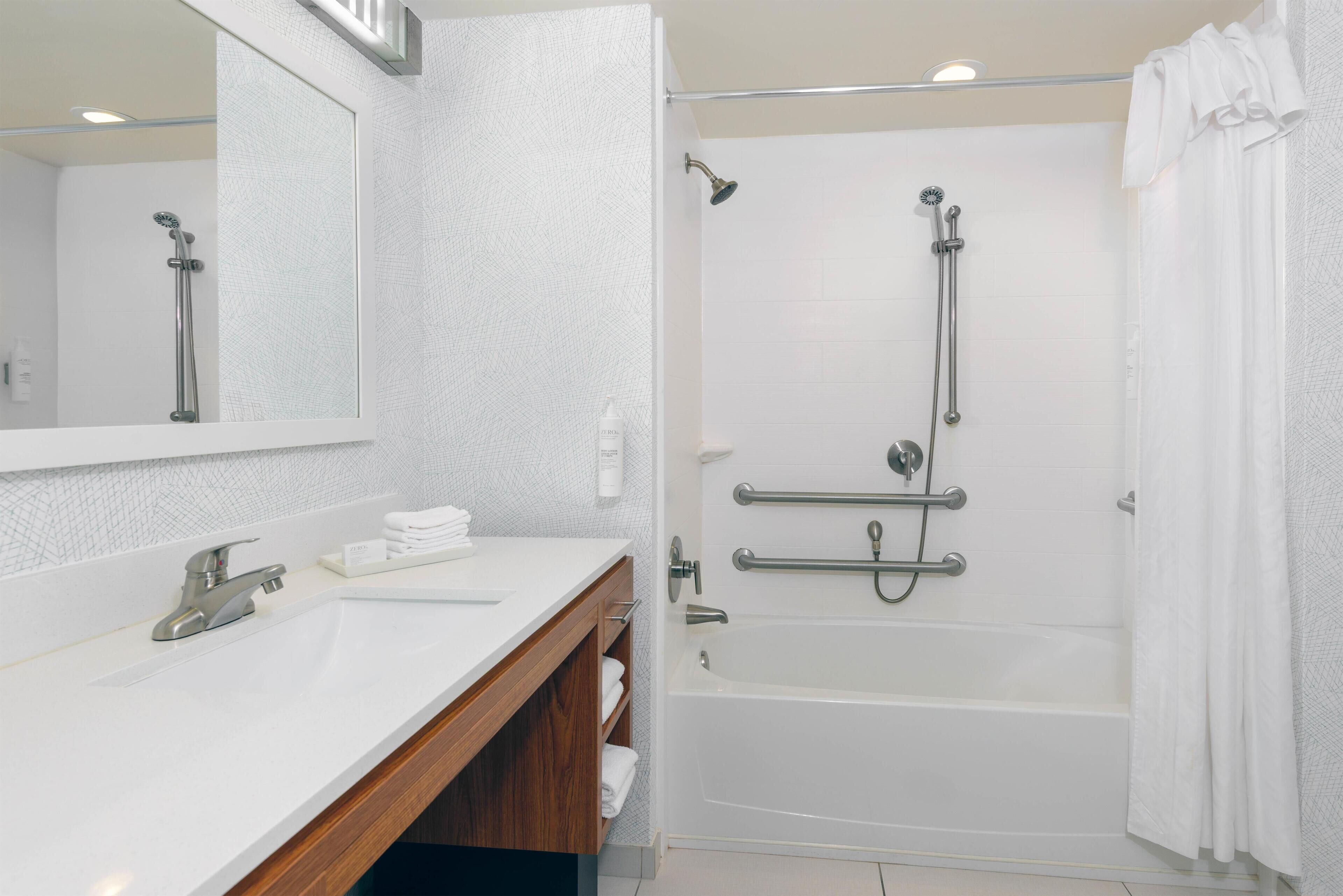 Une salle de bain moderne avec un lavabo blanc, un miroir et une baignoire.