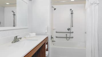 A modern bathroom with a white sink, mirror, and bathtub.