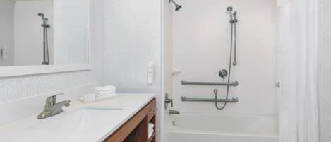 Ein modernes Badezimmer mit Waschbecken, Spiegel und Badewanne in Weiß.