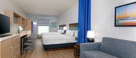 Une chambre d’hôtel équipée d’un lit, d’un bureau, d’une chaise, d’un canapé et d’une télévision.