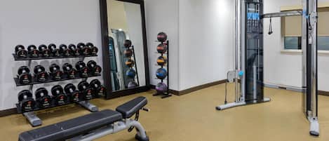Un gimnasio con banco, mancuernas, espejo y equipamiento de ejercicio.