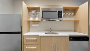 Eine moderne Küche mit einem Edelstahl-Kühlschrank, einer eingebauten Mikrowelle, einem Geschirrspüler und Holzschränken.