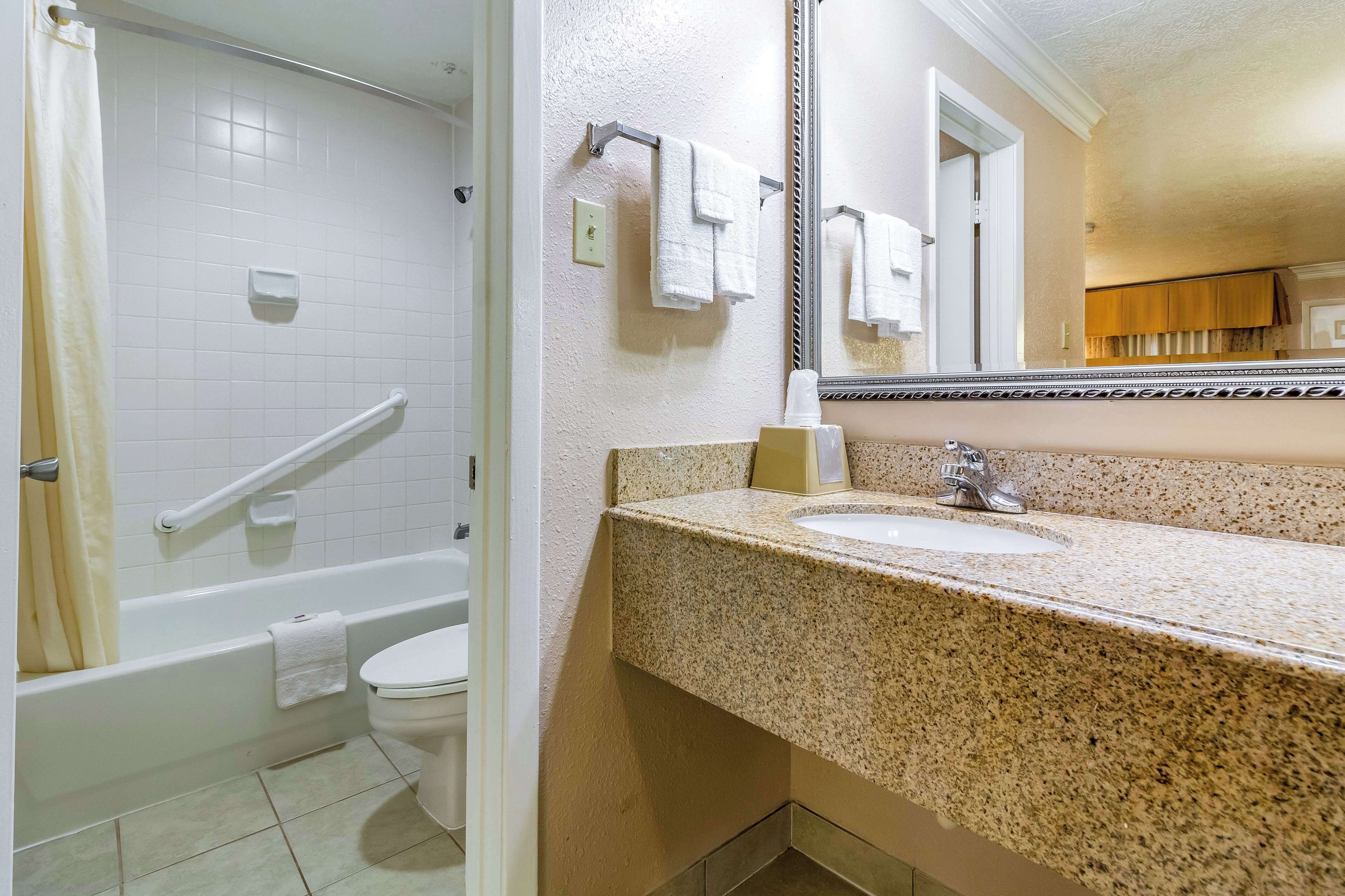 A bathroom with a bathtub, toilet, sink, and a large mirror.