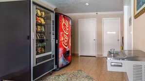 A vending area with a Coca-Cola cooler and a refrigerator stocked with snacks. - Motel 6 Alvin, TX (Alvin)