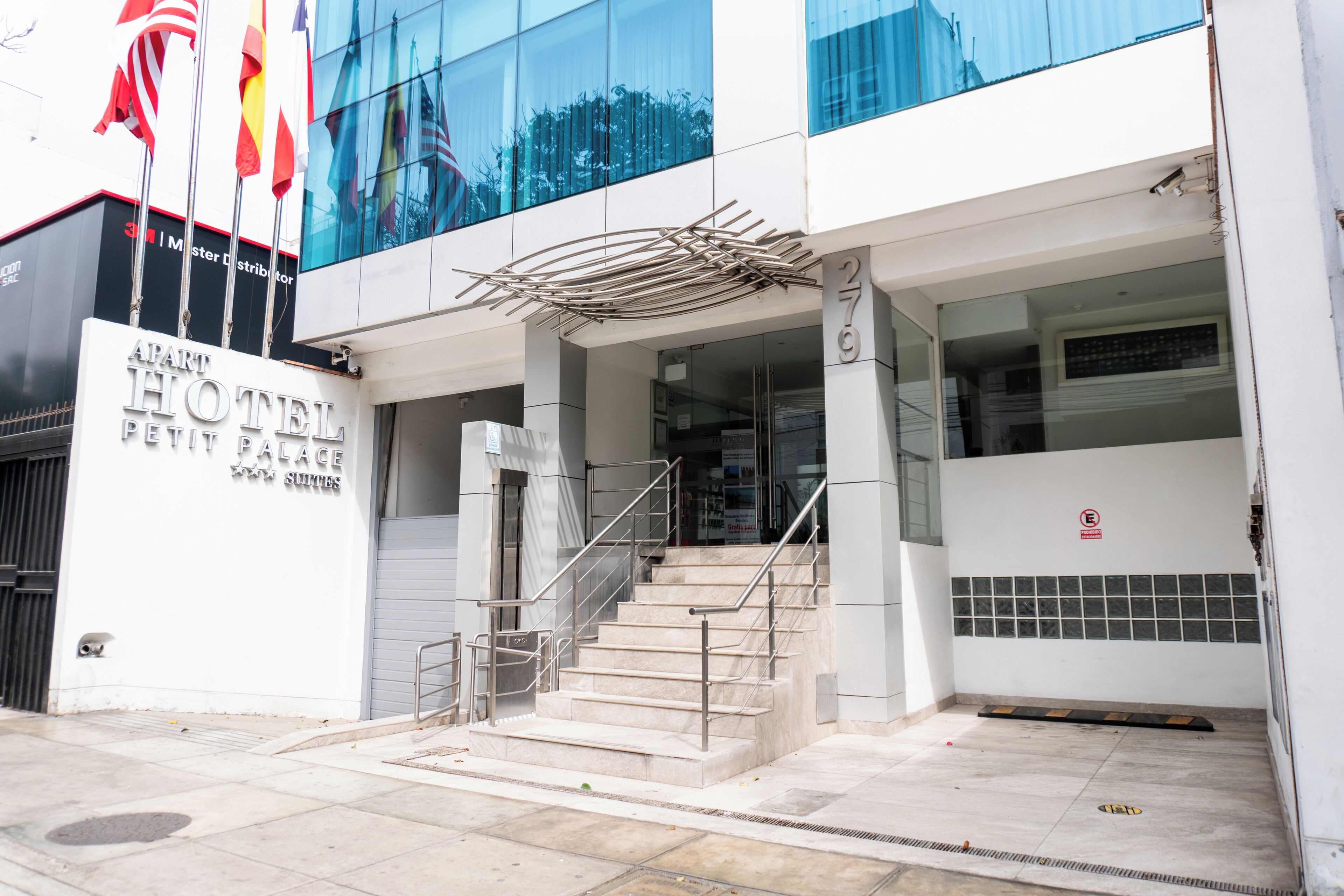 L'esterno dell'APART HOTEL PETIT PALACE, con una scala che conduce all'ingresso, una telecamera di sicurezza e un cartello che vieta di fumare.
