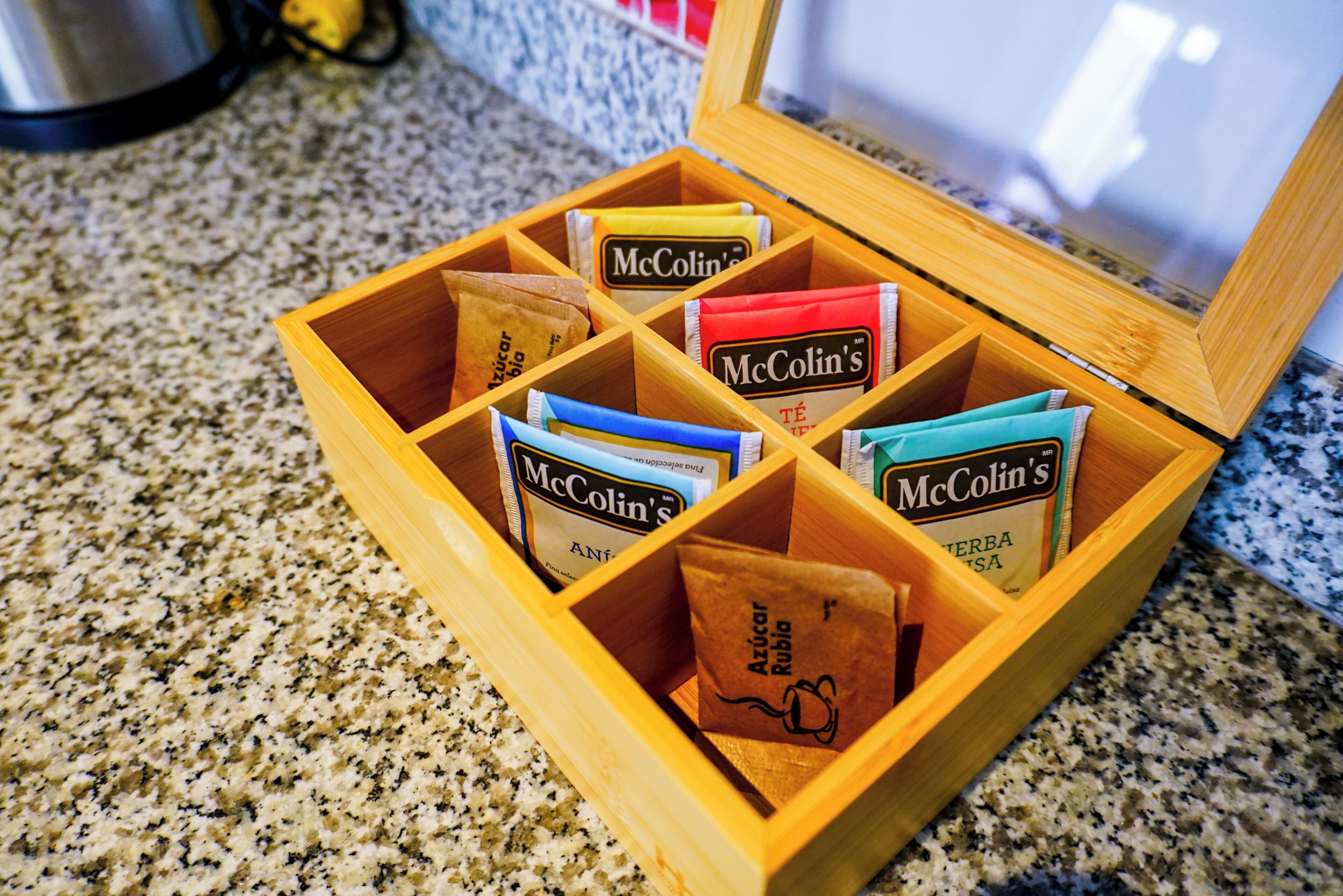 Una scatola di legno con scomparti contenenti bustine di tè McColin.