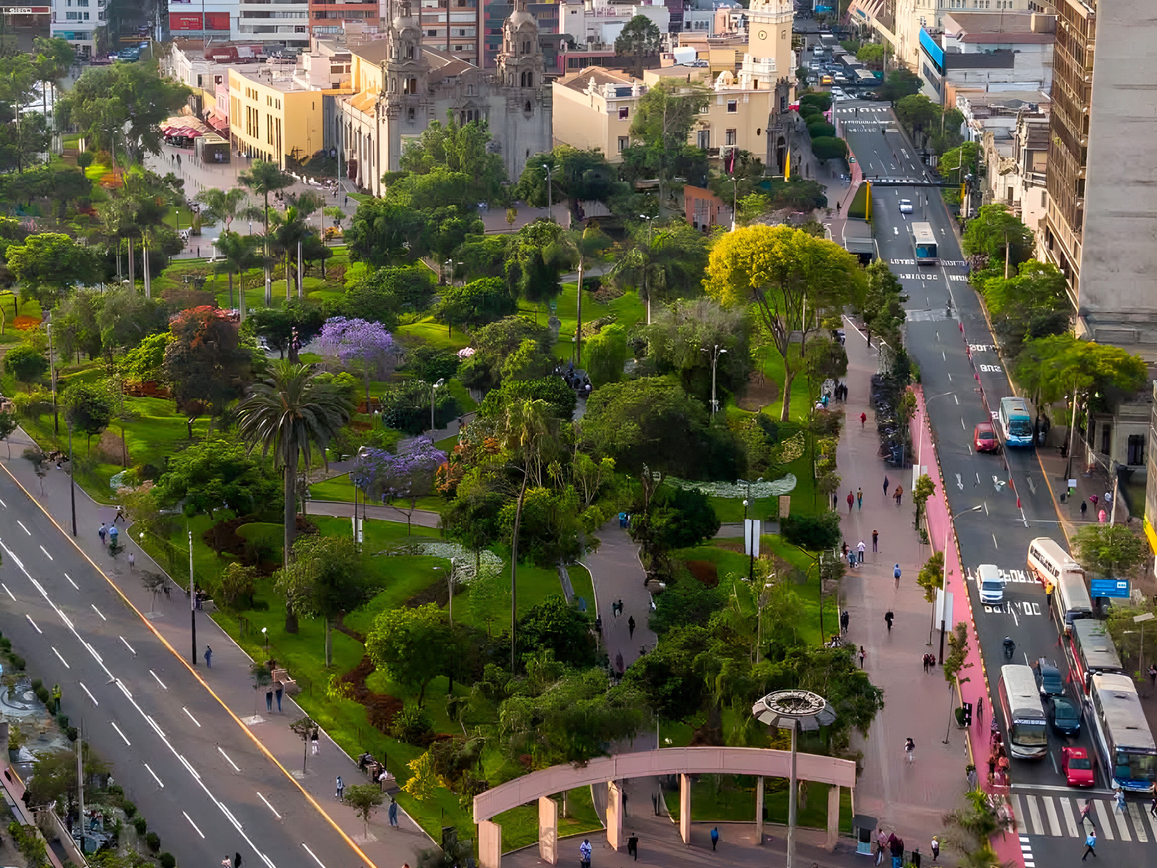 A cityscape with a prominent green park area, a pedestrian bridge, and a busy street with vehicles.