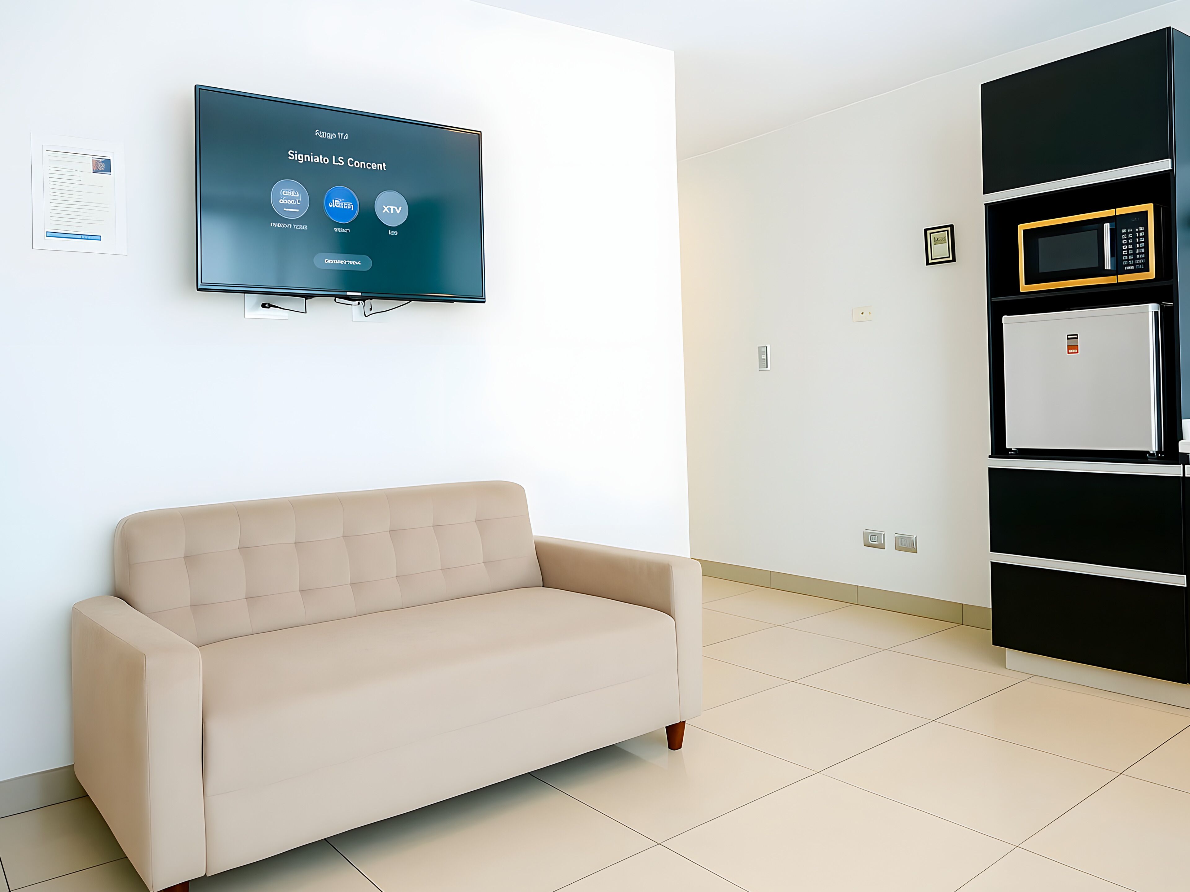A modern living room with a beige sofa, a mounted flat-screen TV displaying a content management system, and a built-in microwave above a black cabinet.