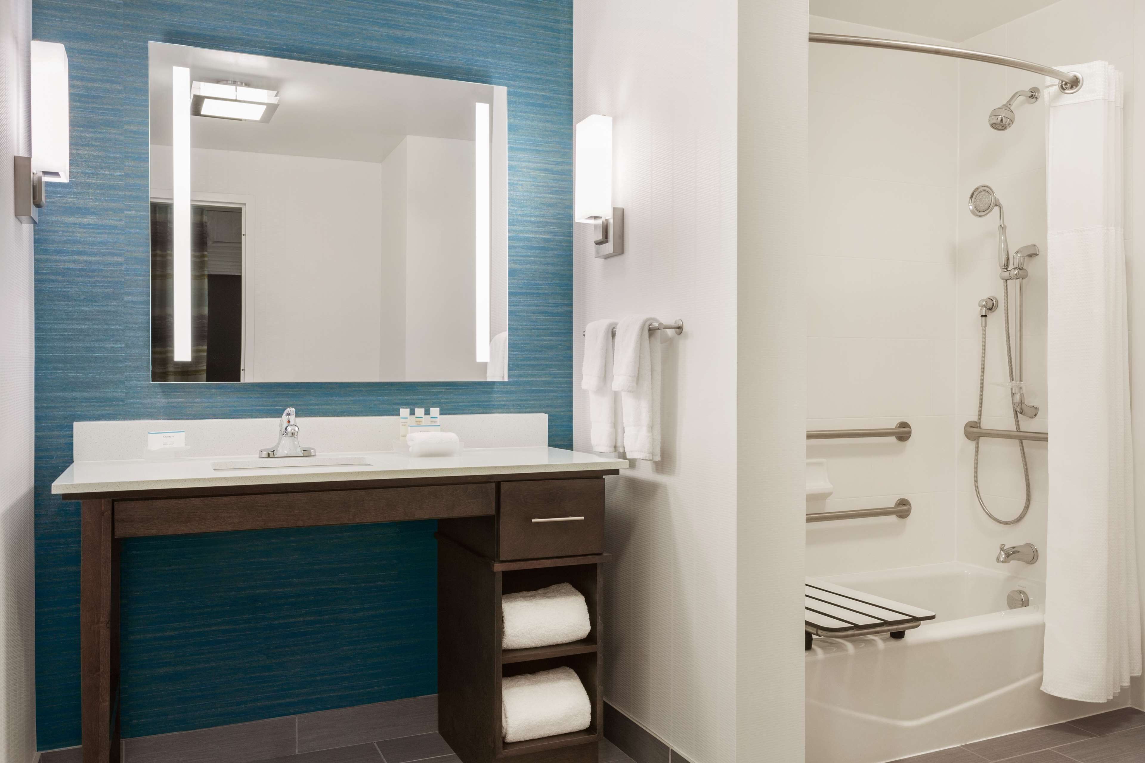 A bathroom with a white sink, a mirror, a towel rack, and a shower with a glass door.