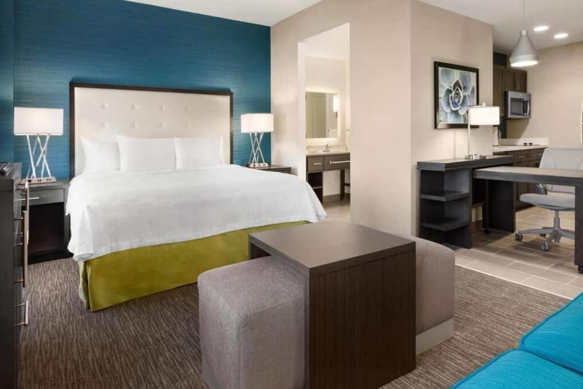 Una habitación de hotel con una cama, un escritorio, una silla, una mesita y un sofá.