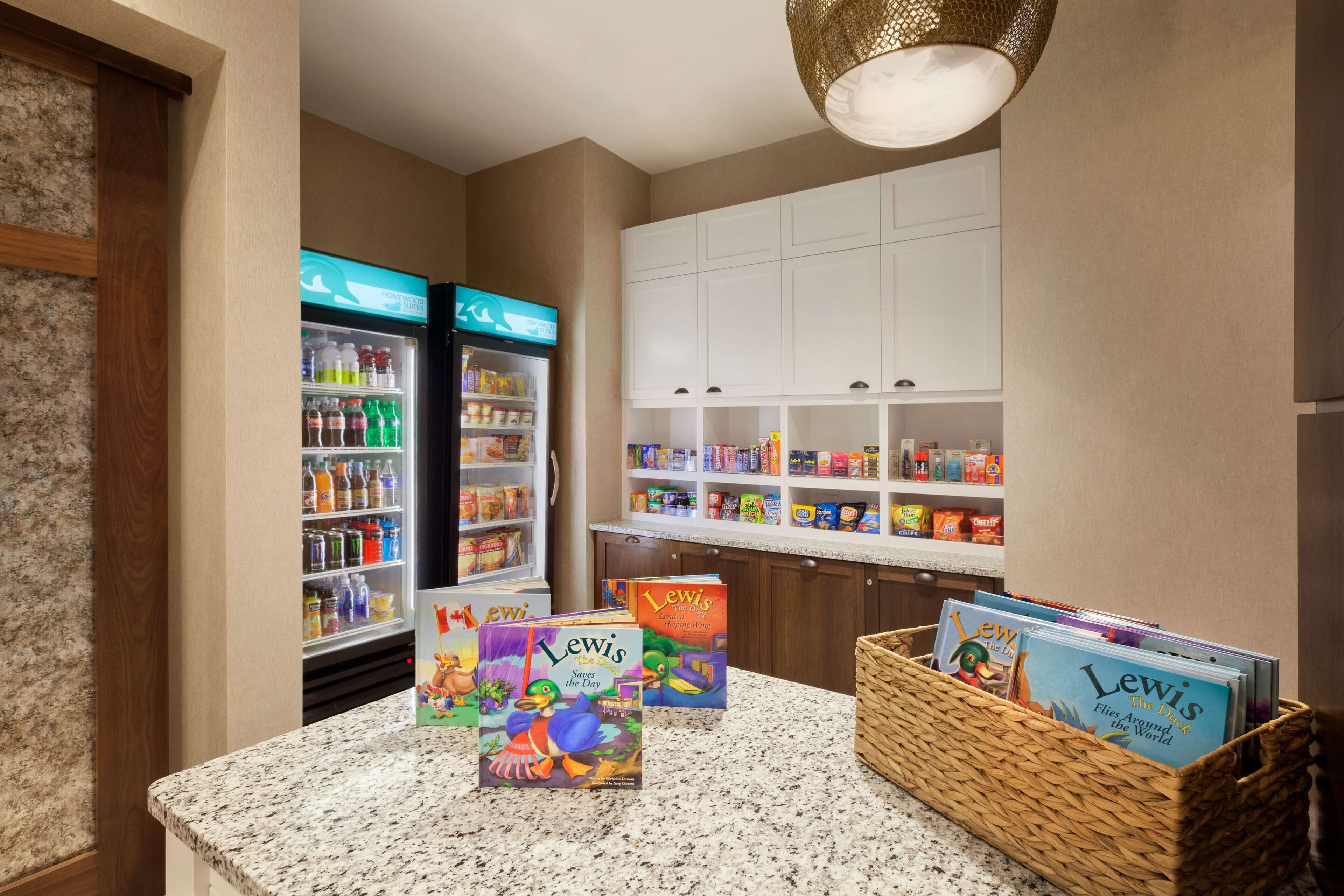 Un coin cuisine doté de plans de travail en granit, d’un réfrigérateur et d’un réfrigérateur à boissons. On y trouve des livres sur le plan de travail et un panier rempli de magazines.