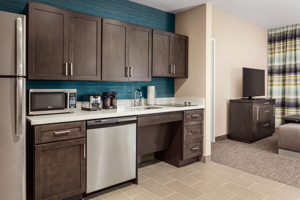 A compact kitchen with dark cabinets, a microwave, a coffee maker, and a dishwasher.