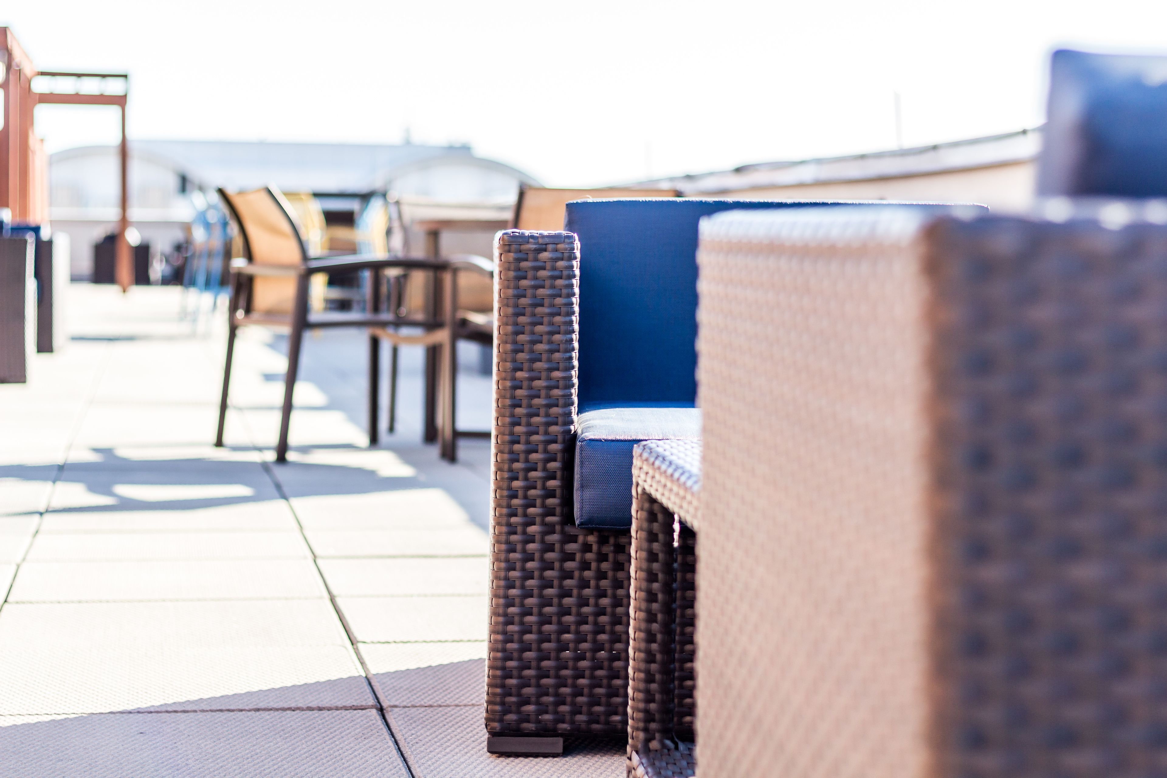 Outdoor wicker furniture with cushions, arranged on a tiled patio.