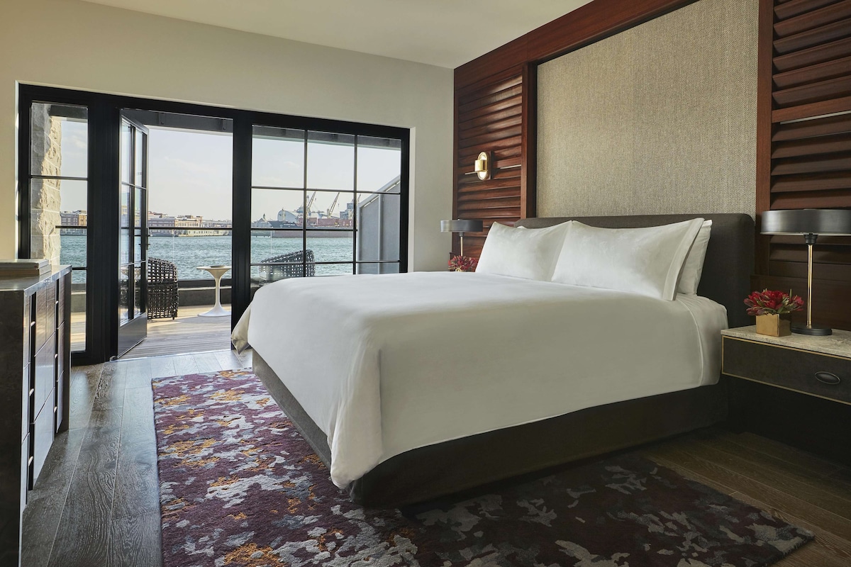 Une chambre d’hôtel moderne avec un grand lit, une vue sur l’eau et un balcon.