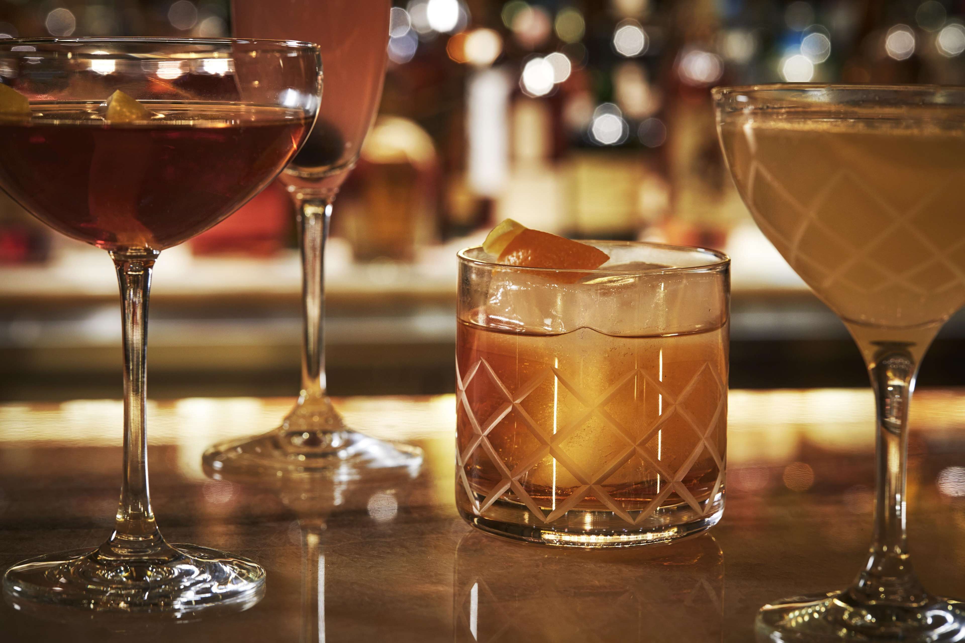 Three glasses of different beverages on a bar counter.