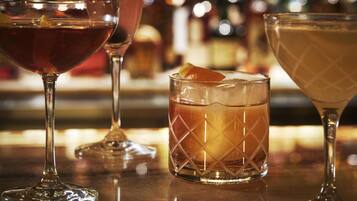 Three glasses of different beverages on a bar counter.