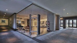 A modern gym with mirrored walls, exercise equipment, and a view of the city through large windows.