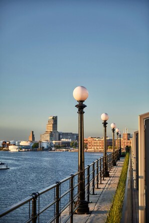 A waterfront promenade with a row of lamp posts and a railing along the edge. - Pendry Baltimore (Baltimore)