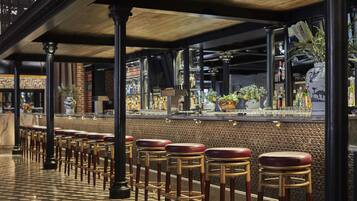 A bar area with a checkered floor, wooden stools, and a bar counter with various bottles and a decorative vase.