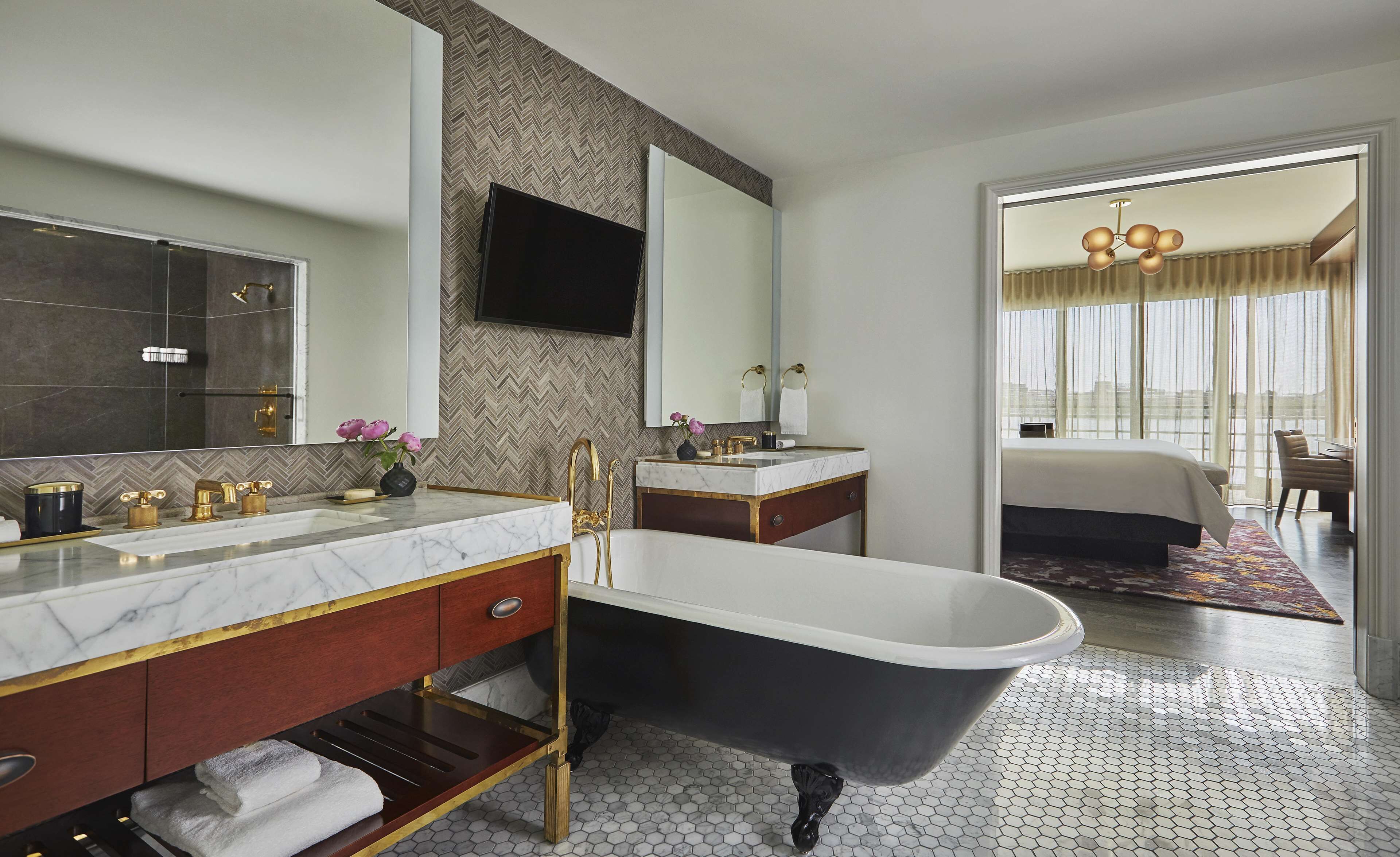 Un baño moderno con una bañera independiente, un tocador con un espejo grande y un revestimiento de pared con diseño de espiga.