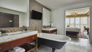 Un baño moderno con una bañera independiente, un tocador con un espejo grande y un revestimiento de pared con diseño de espiga.