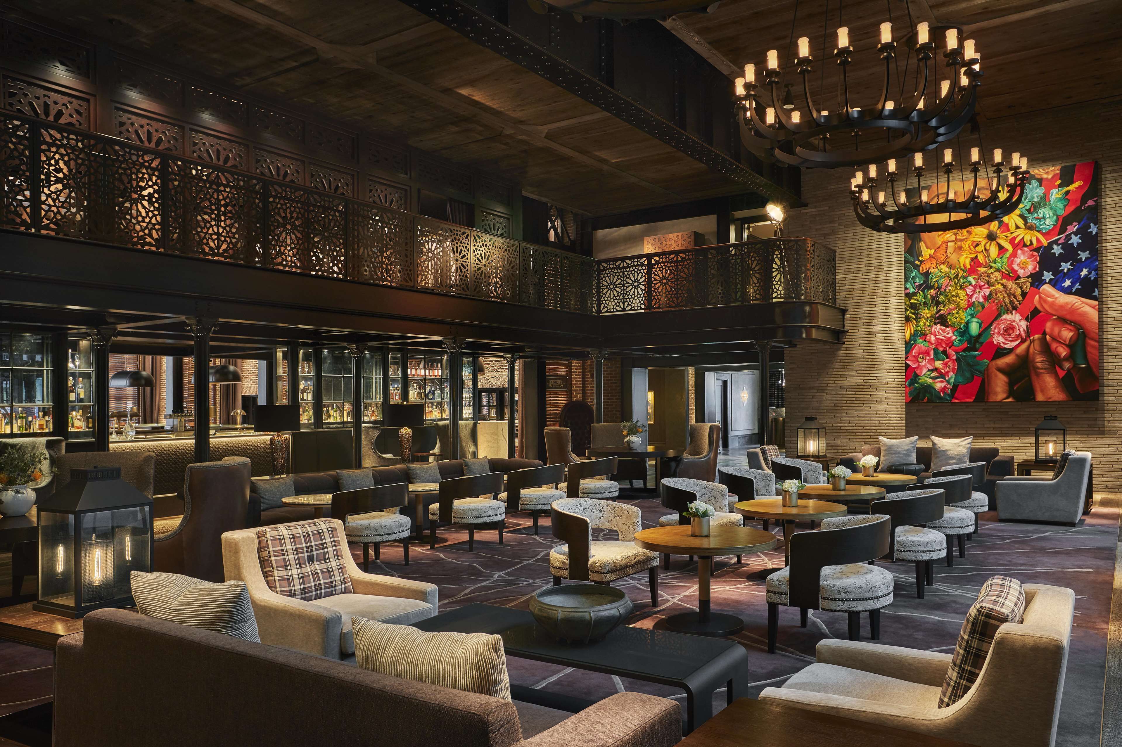 A spacious lobby with multiple seating areas, a bar, and a large decorative wall.