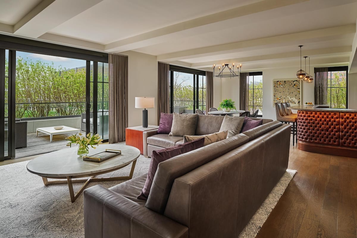 A modern living room with a large sofa, a dining area, and a kitchen with a red bar.
