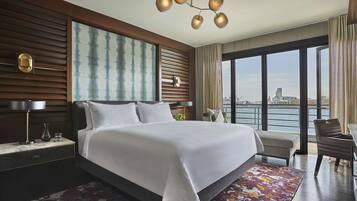 A modern hotel room with a large bed, a view of the city, and a cityscape visible through the windows.