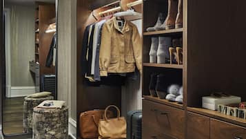 A hotel room with a wooden wardrobe, a mirror, a bench, and a suitcase.