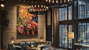 A modern lounge area with round tables, cushioned chairs, and a large floral painting on the wall. - Pendry Baltimore (Baltimore)