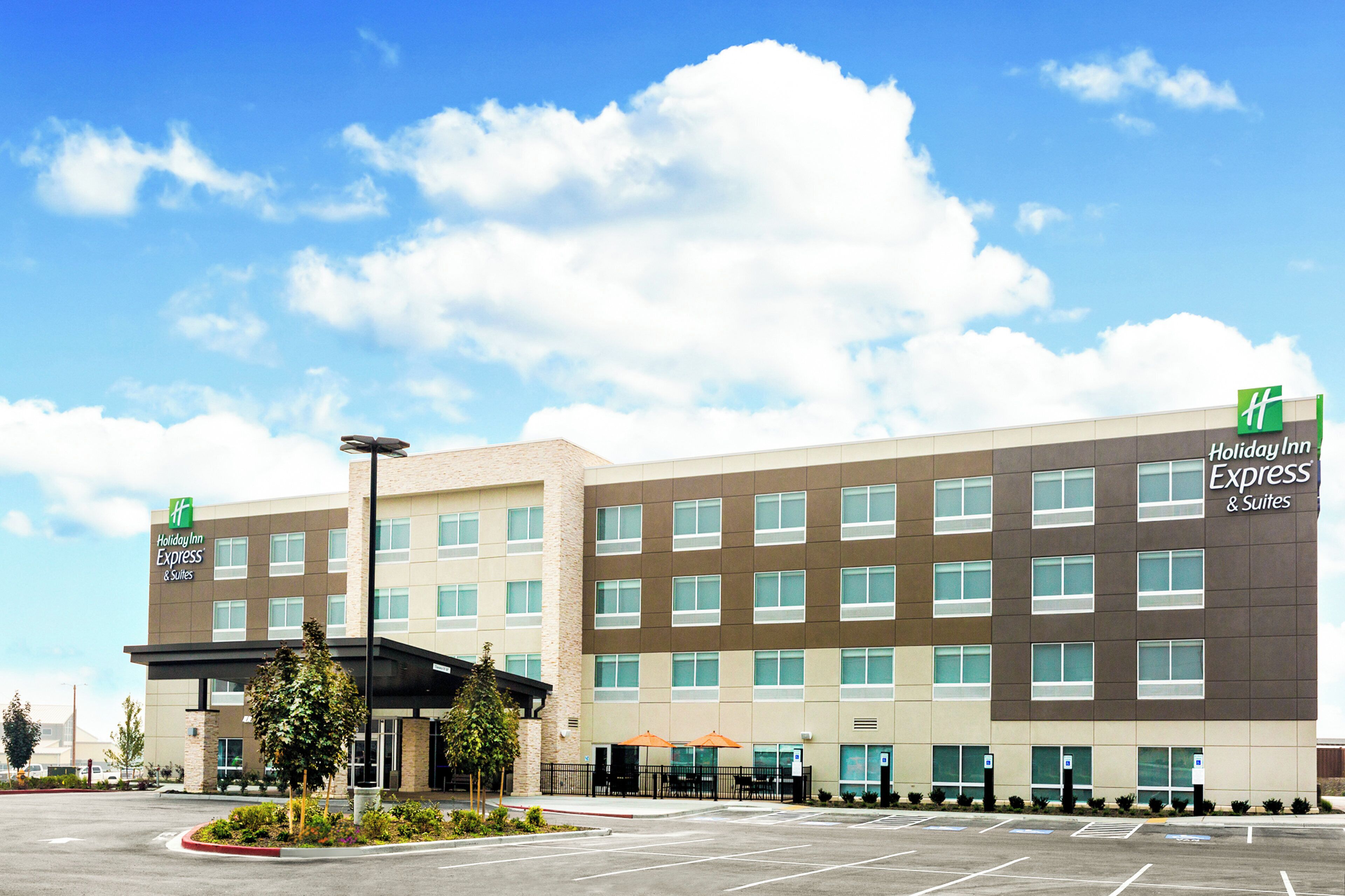 A Holiday Inn Express & Suites hotel with a parking lot and a clear sky.