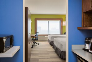 Une chambre d’hôtel équipée d’un bureau, de deux lits, d’un four à micro-ondes et d’une machine à café.