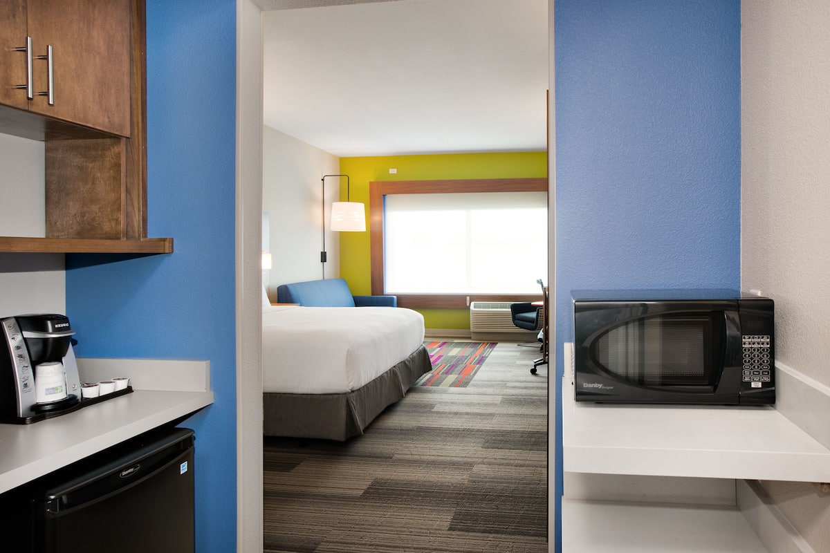 Ein Hotelzimmer mit Bett, Mikrowelle, Kaffeemaschine und Schreibtisch.