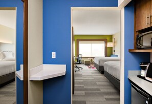 Une chambre d’hôtel avec deux lits, un bureau, un four à micro-ondes et une fenêtre donnant sur un paysage agréable.