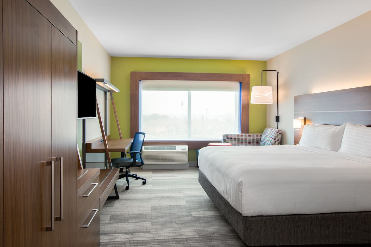 Ein Hotelzimmer mit Bett, Schreibtisch, Stuhl und einem großen Fenster.