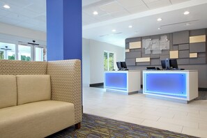 A hotel reception area with a sofa, two reception desks, and a blue pillar. - Holiday Inn Express & Suites Columbus North by IHG (Columbus)