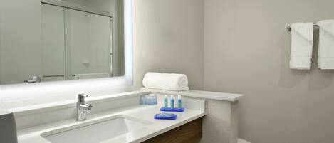 Un baño moderno con lavamanos, espejo y retrete blancos.
