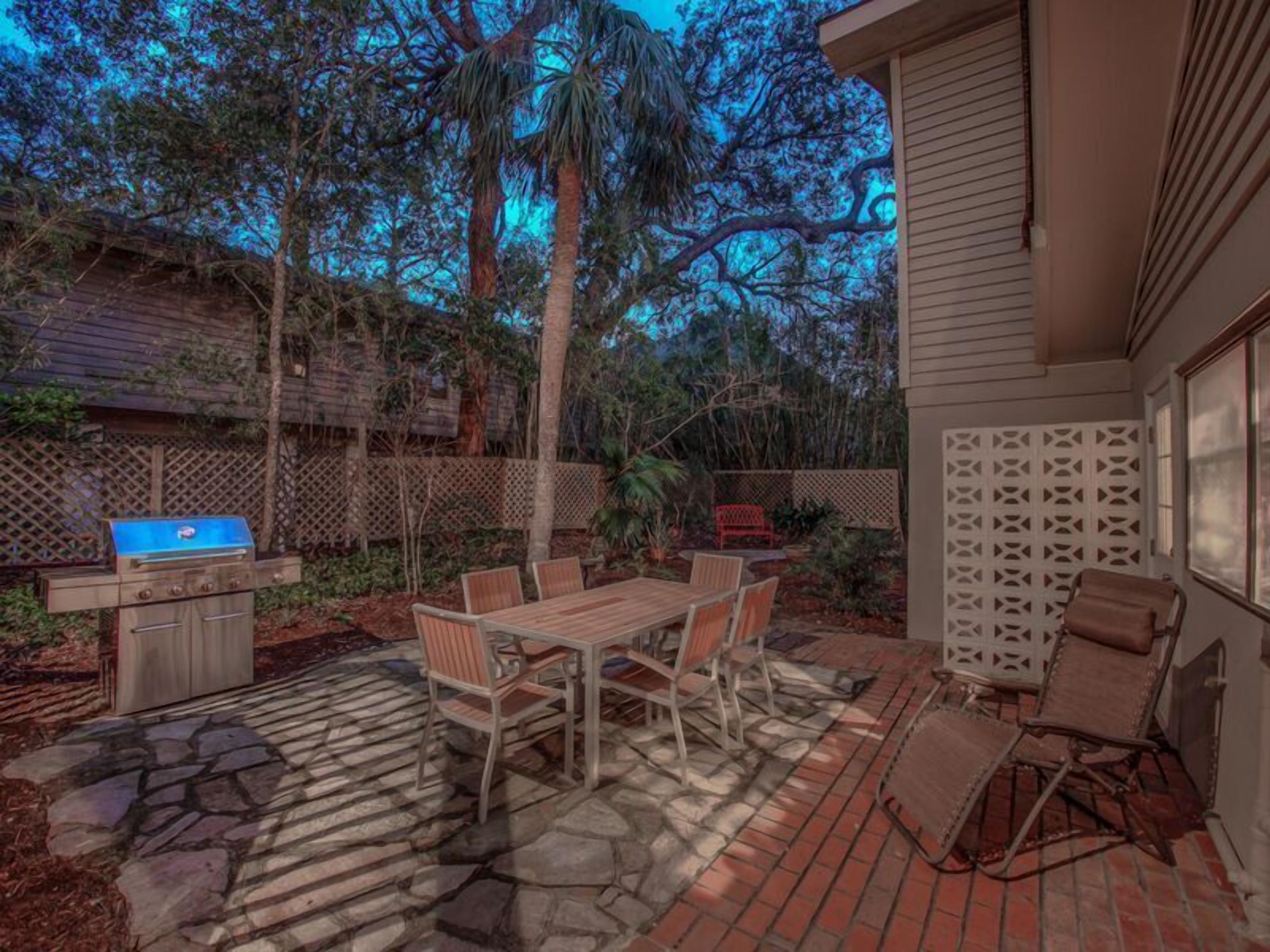 An outdoor patio with a grill, dining table, and chairs.