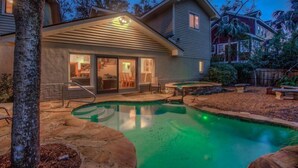 A house with a swimming pool, a covered patio, and a view of neighboring houses.