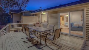 A deck with a table and chairs, a sliding glass door leading to a living room with a couch.