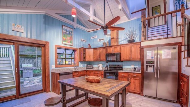 A kitchen with wooden cabinets, a stainless steel refrigerator, a microwave, and a large island with a basket.