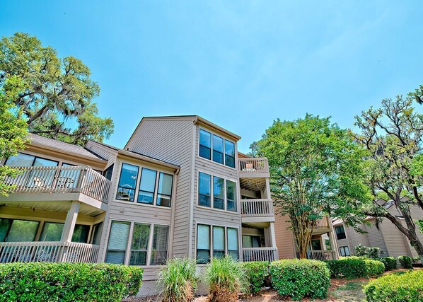 A multi-story residential building with balconies, large windows, and a well-maintained garden.