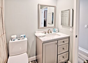 A bathroom with a toilet, sink, and mirror.