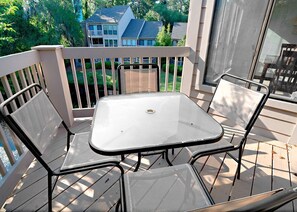 A balcony with a table and chairs, overlooking a residential area.