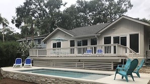 A house with a swimming pool, a covered patio with chairs, and a stone retaining wall. - Palmetto Paradise 3 Bedroom Holiday Home (Hilton Head Island)