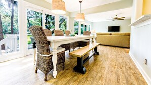 A dining area with wicker chairs, a wooden bench, and a white table. - Palmetto Paradise 3 Bedroom Holiday Home (Hilton Head Island)
