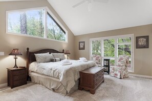 Een slaapkamer met een groot bed, twee nachtkastjes, een dressoir, een stoel en een raam met jaloezieën.