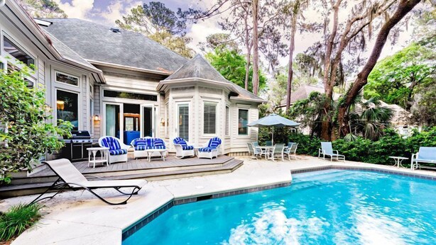 A swimming pool with lounge chairs and a patio area. - Su Casa 5 Bedroom Holiday Home (Hilton Head Island)
