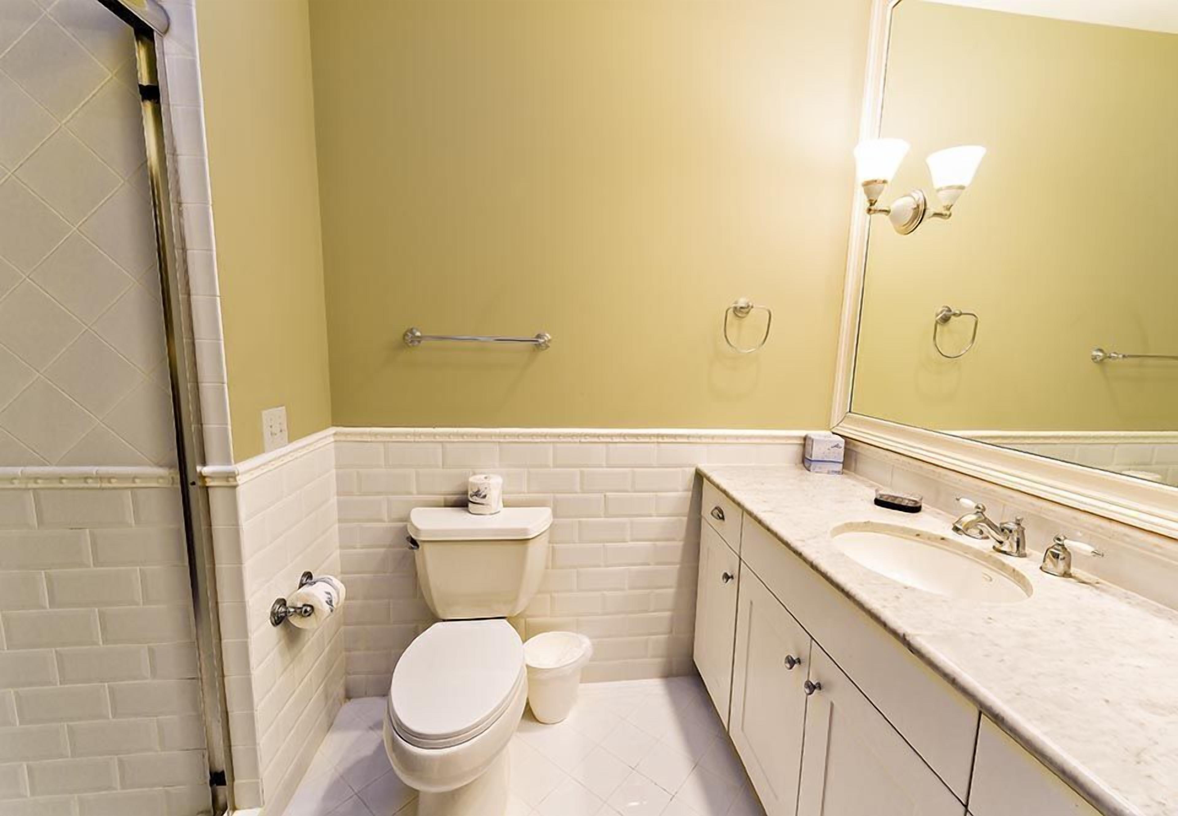 A bathroom with a toilet, sink, and mirror.